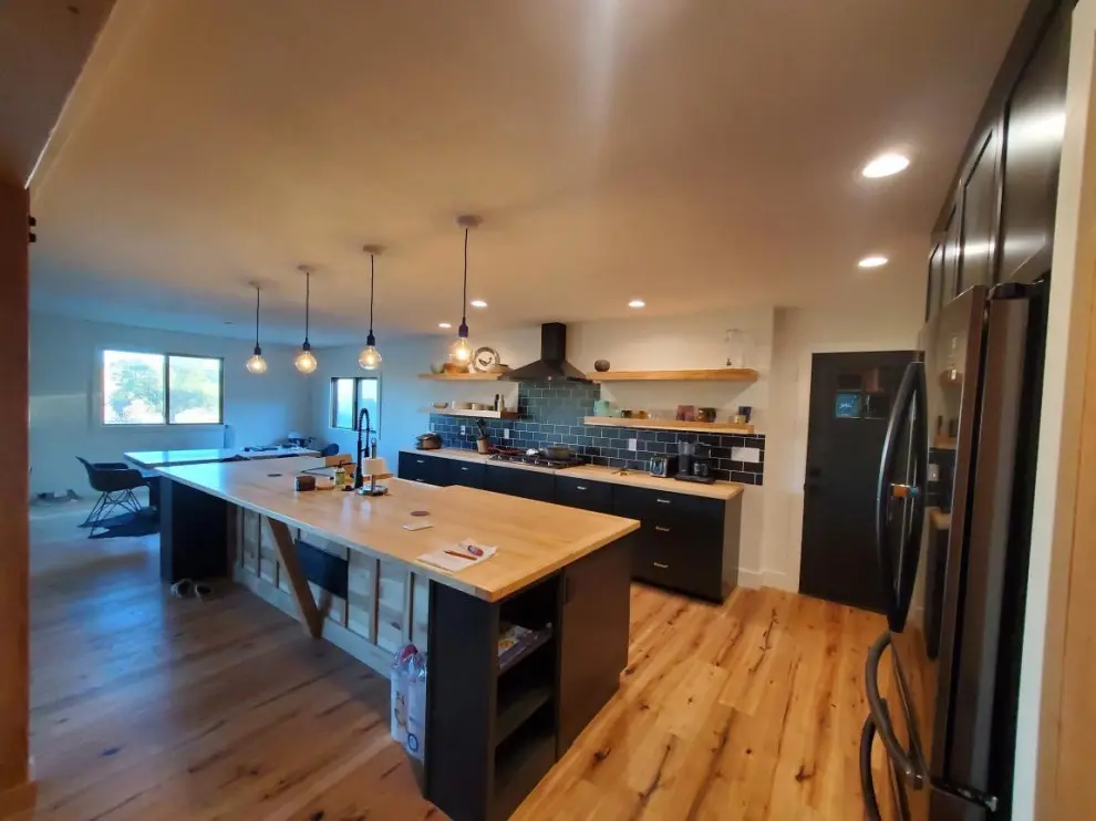 Modern kitchen with wooden island and lighting.