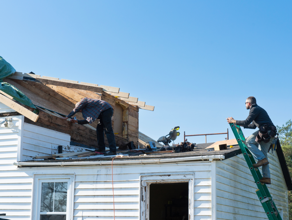Workers repairing roof on sunny day.